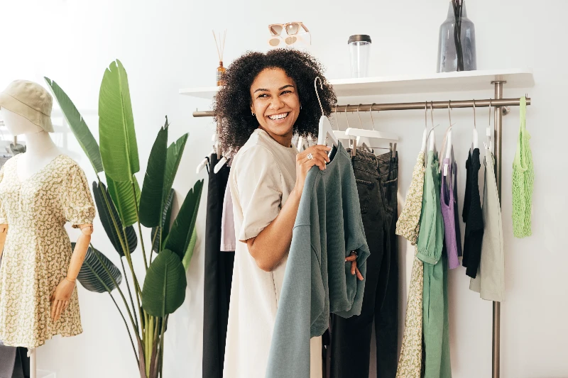 Laughing woman customer choosing sweatshirt in store